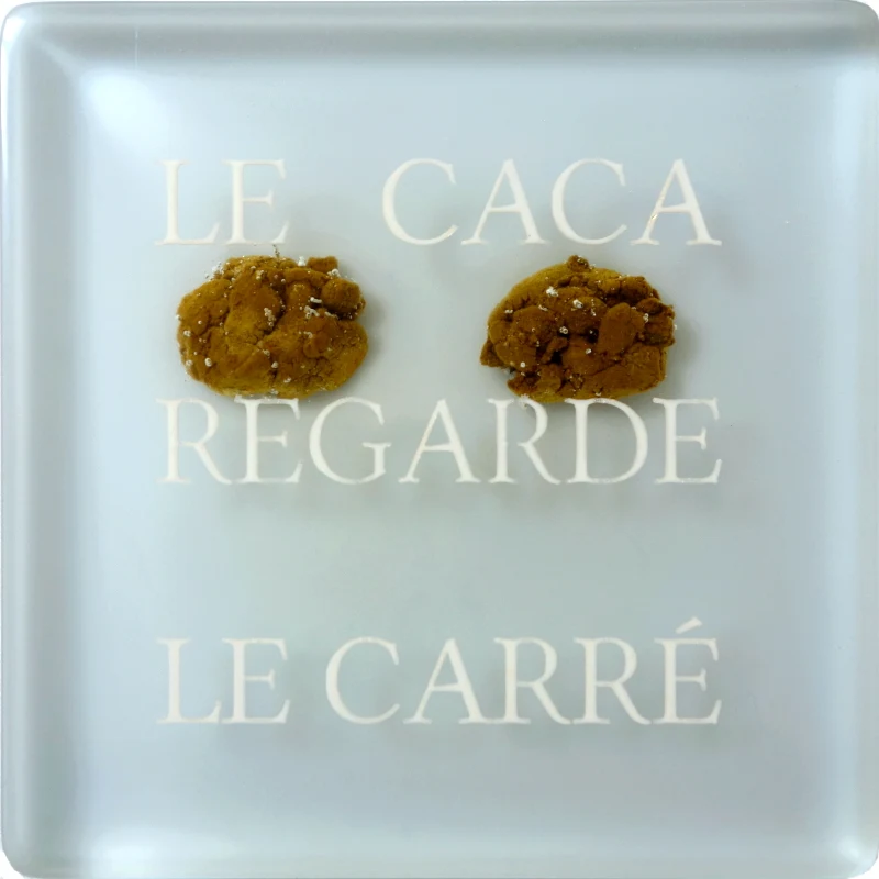 Un tableau carré en verre peint en blanc sur l'envers. La peinture est grattée pour écrire : . Vue de détail.