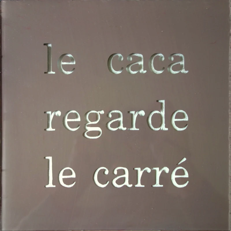 Un tableau carré en verre peint en brun sur l'envers. La peinture est grattée pour écrire : le caca regarde le carré. Vue de face.