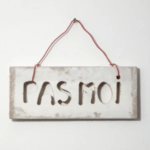 Une planche accrochée au mur avec des lettres découpées disant "pas moi"